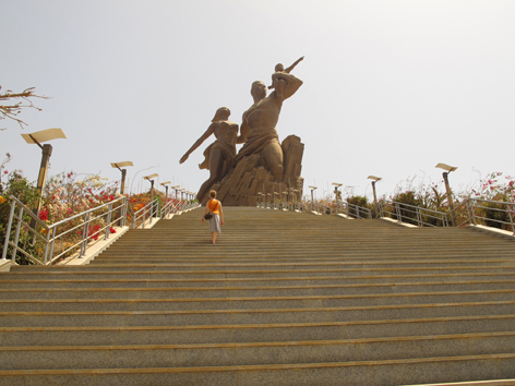 Female tourist climbs the stairs to Dakar's African Renaissance Monument, Senegal