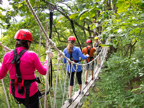 Participants cross a rope bridge on the Navitat Canopy zipline course, Asheville