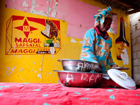 African woman cooking in front of a Maggi cube sign