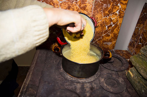 Adding corn flour to boiling water to make Romanian mamaliga.