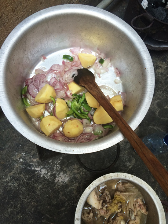 Preparing ingredients in a pot for chicken pilau in Zanzibar