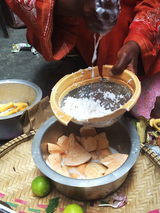 Woman grating coconuts to make a sweet potato dessert in Zanzibar