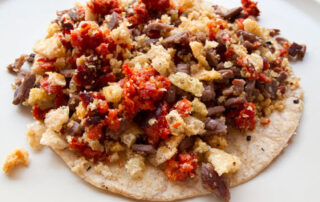 A colorful taco de campechano in Mexico City combines grilled beef, chicharrón, and longaniza sausage in a tortilla.