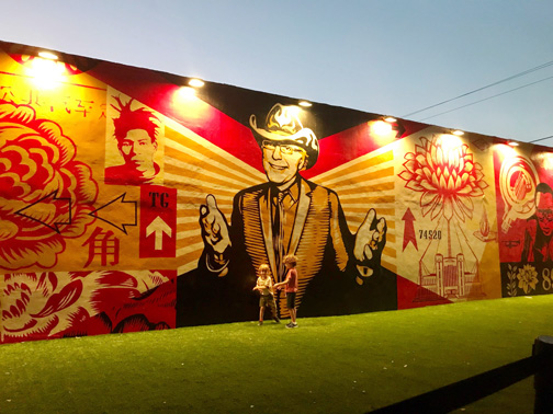 The Shepard Fairey mural at the Wynwood Walls with two kids playing in front of it.