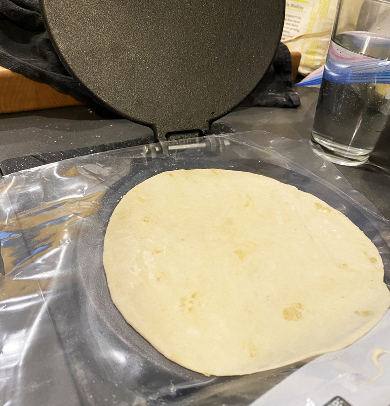 Tortilla press in use with flattened dough