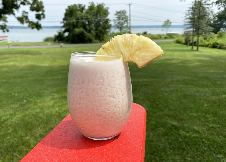 The Dirty Banana tropical cocktail pictured in front of Cayuga Lake in New York.