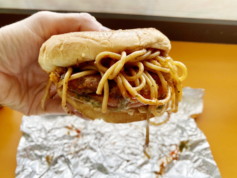 Noodles spilling out of the vegetarian Punjabi burger in Richmond Hill, Queens