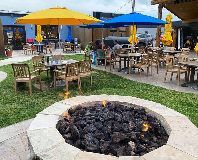 The outdoor dining setup at Alibi Wood-Fire Pizzaria in Laramie includes fire pits and tables.