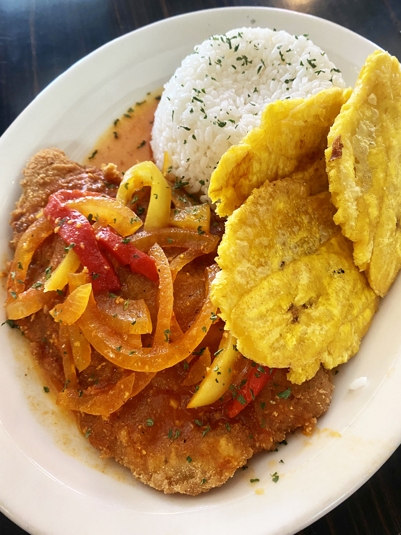 Filet de mero empanado, a fried fish dish, served with rice and tostones from a restaurant in Puerto Rico.
