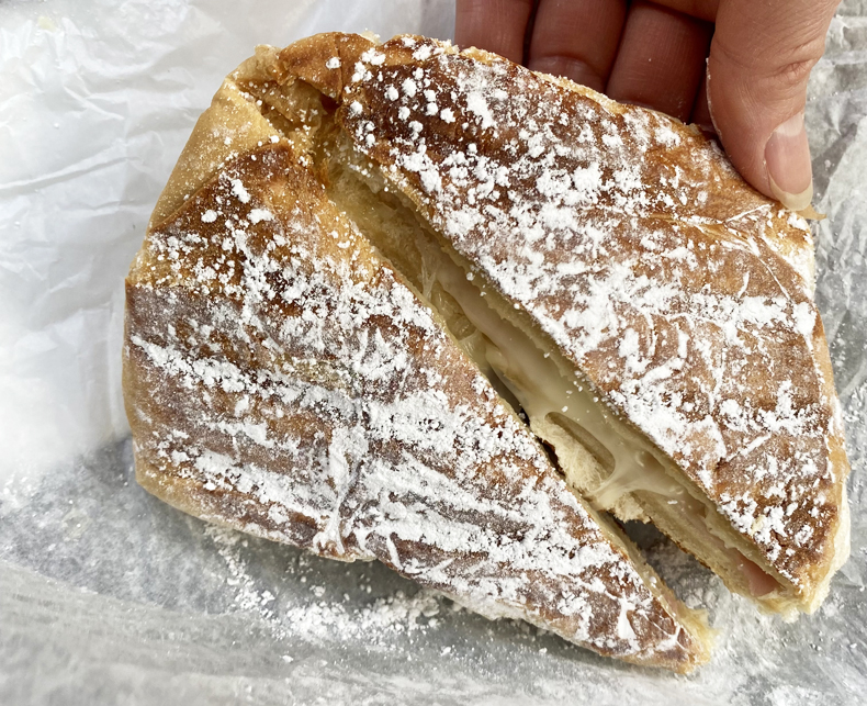 A powdered sugar-dusted mallorca, with melted cheese and ham inside, from Old San Juan, Puerto Rico