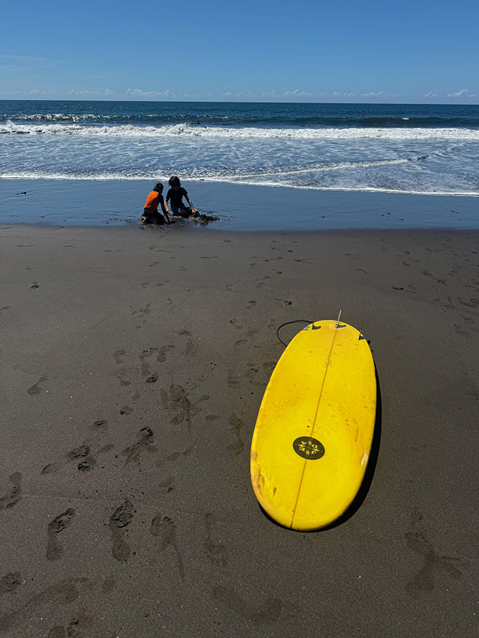 Two kids and a surfboard on an empty beach, Playa Sunzal, in El Salvador